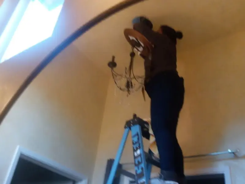 Electrician installing a chandelier in a Westview residence